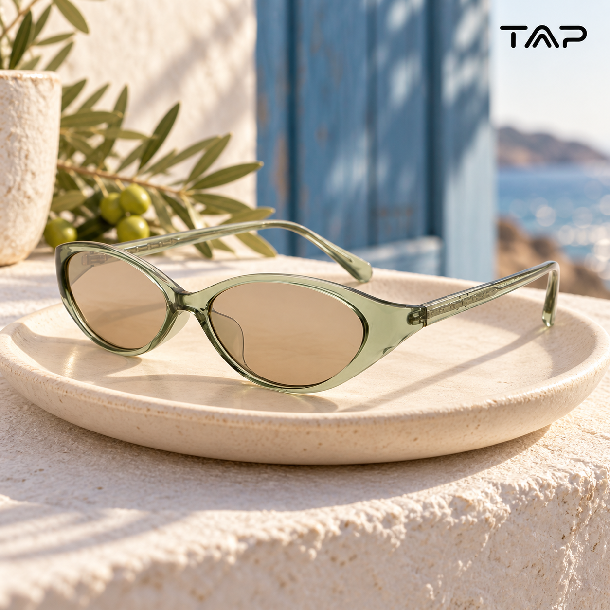Translucent sage cat-eye sunglasses on a cream ceramic dish